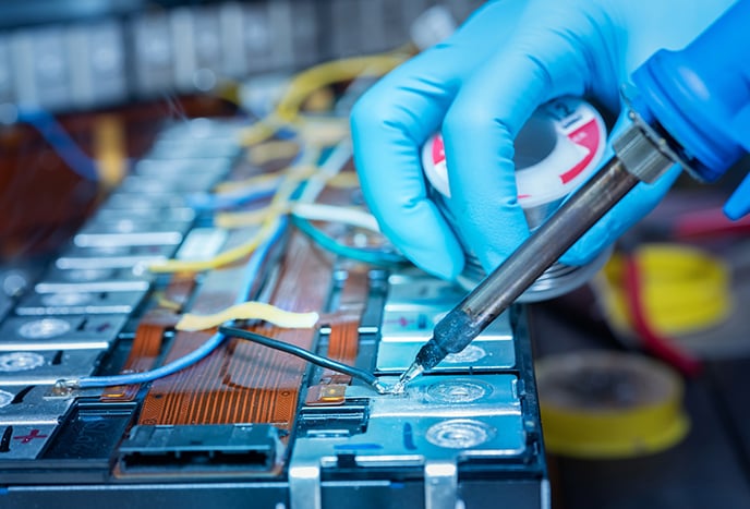 Hands of an assembly line employee soldering a battery array