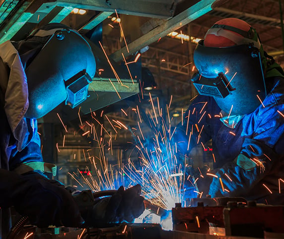 Two welding professionals work together to fuse a manufactured part