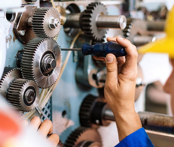 A set of gears gets some maintenance by a worker
